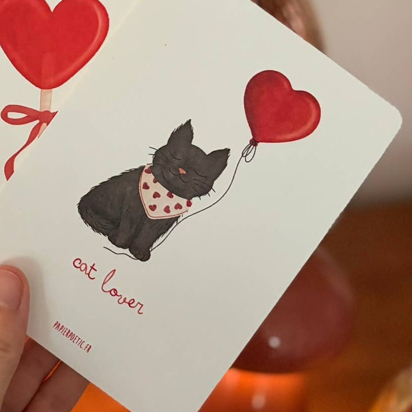 Hand holding playing cards with dog and heart designs on a wooden surface.