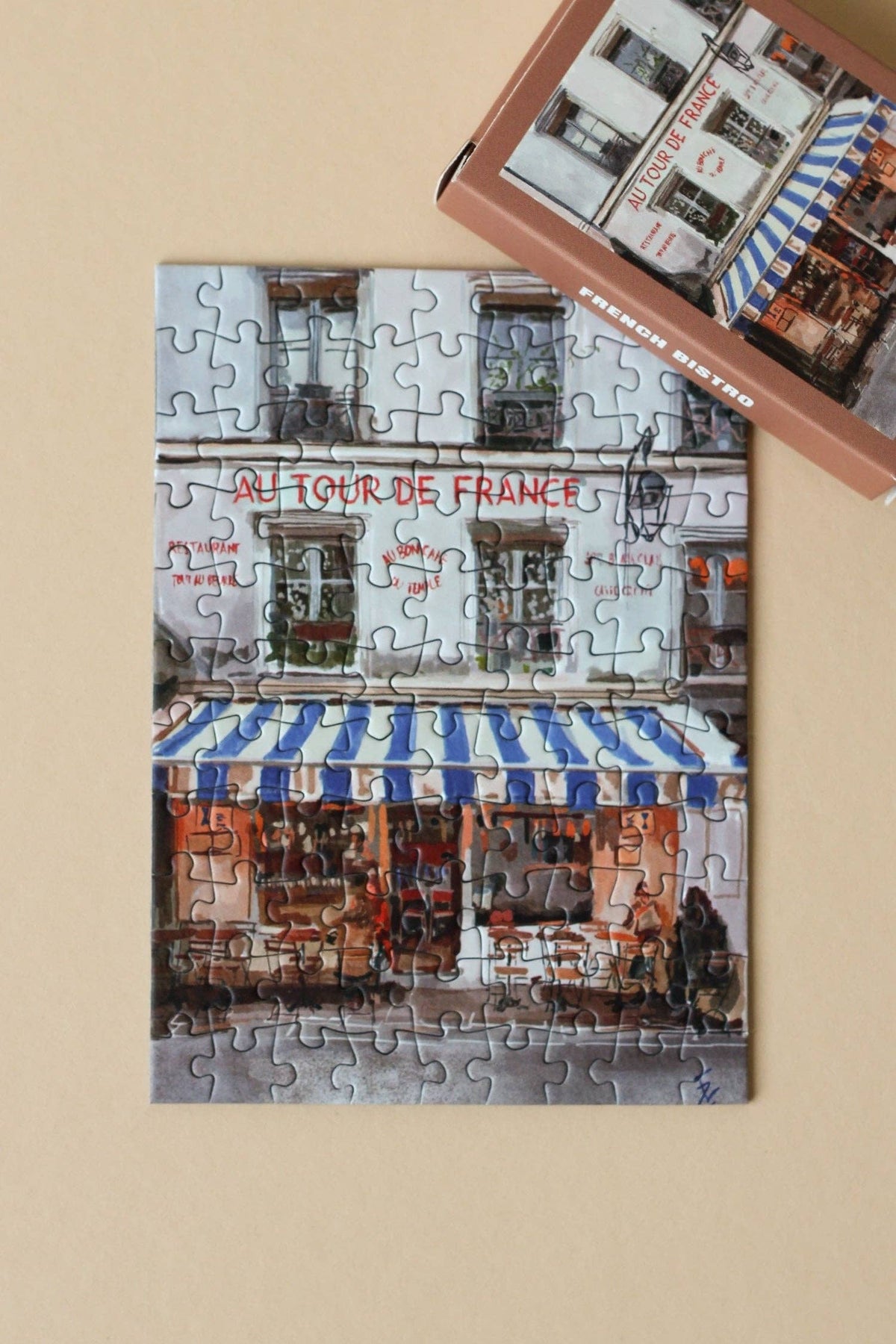 Jigsaw puzzle of a Parisian street scene with a completed section on a beige surface