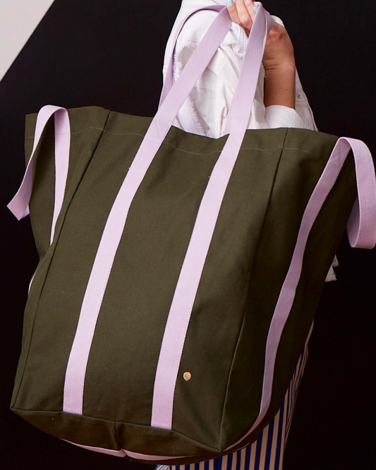 An olive green canvas tote bag with vertical lavender purple stripes and matching lavender shoulder straps, shown against a plain white background.