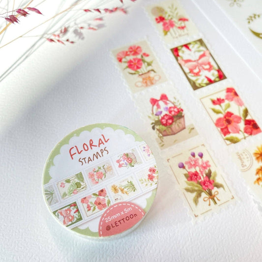 A set of floral washi tapes arranged on a textured white background, alongside a sheet of decorative washi tapes featuring a gold crescent moon and floral motifs, accented by dried pink flowers in the corners.