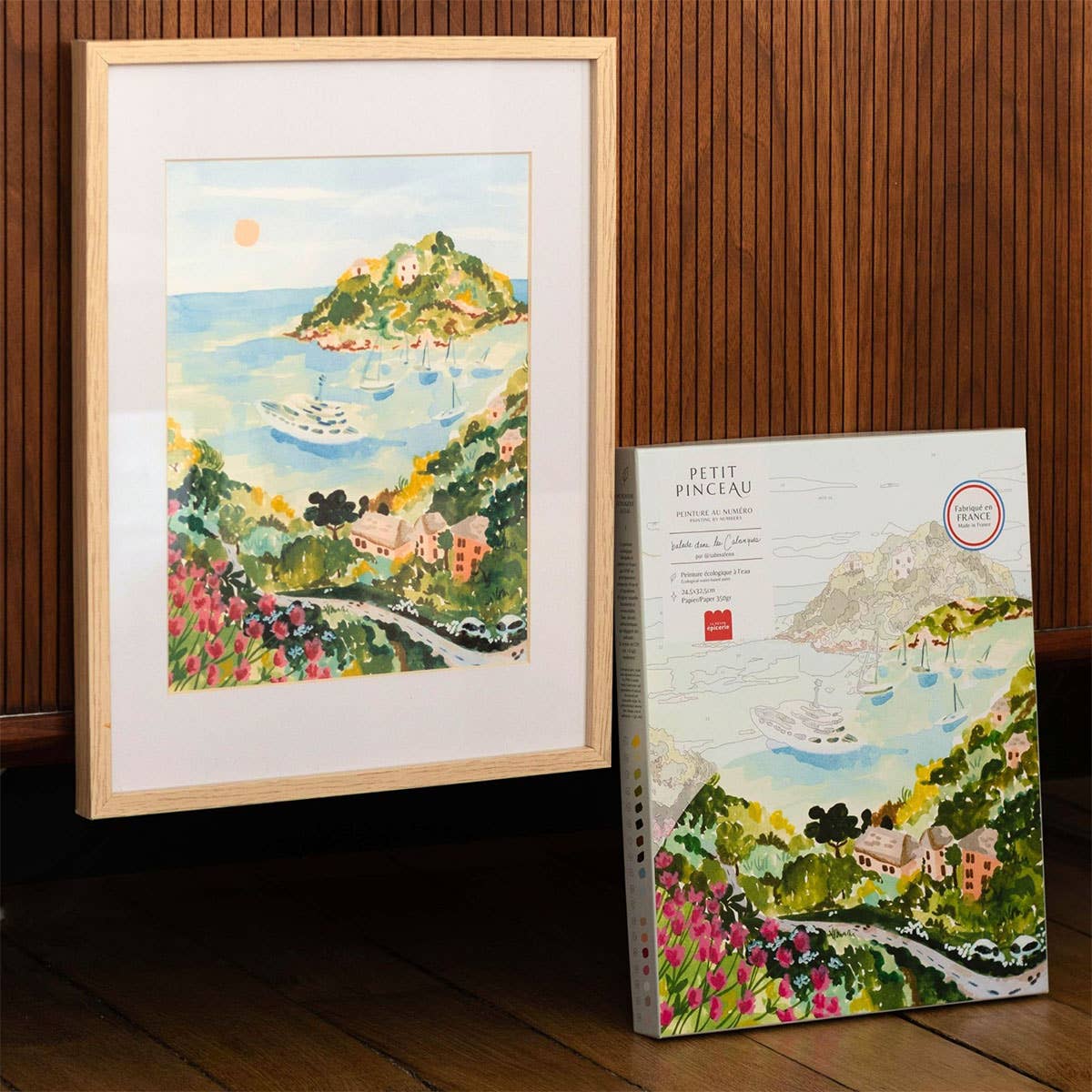 Framed artwork of a coastal scene with a matching box on a wooden surface