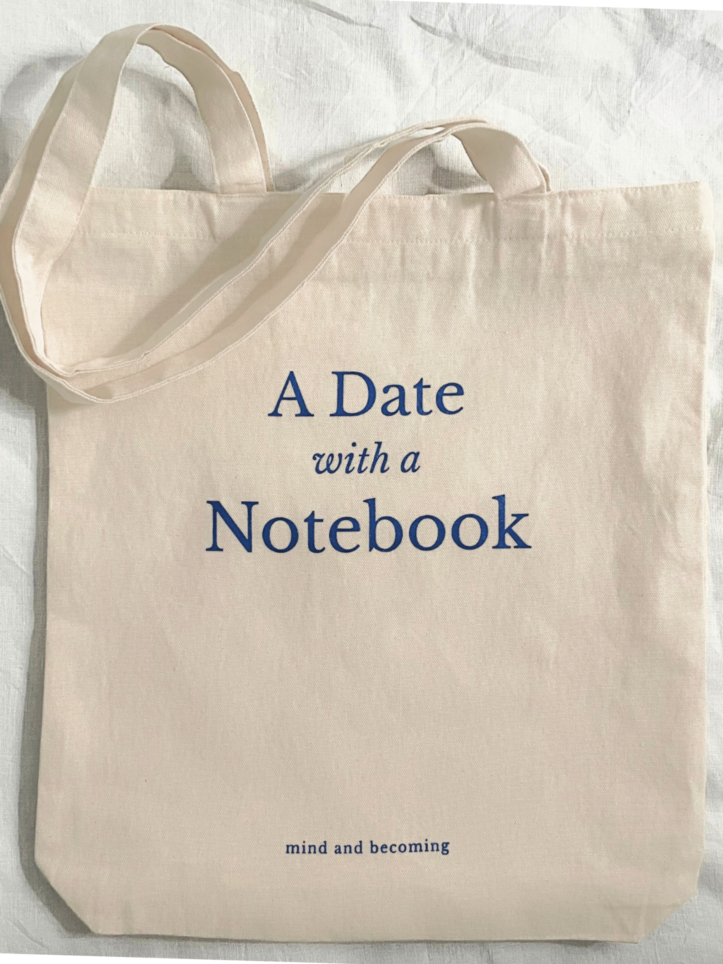 Beige tote bag with 'A Date with a Notebook' text on a light background