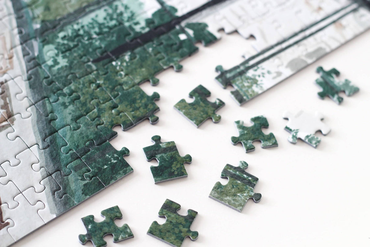 Jigsaw puzzle with green and white pieces on a white surface