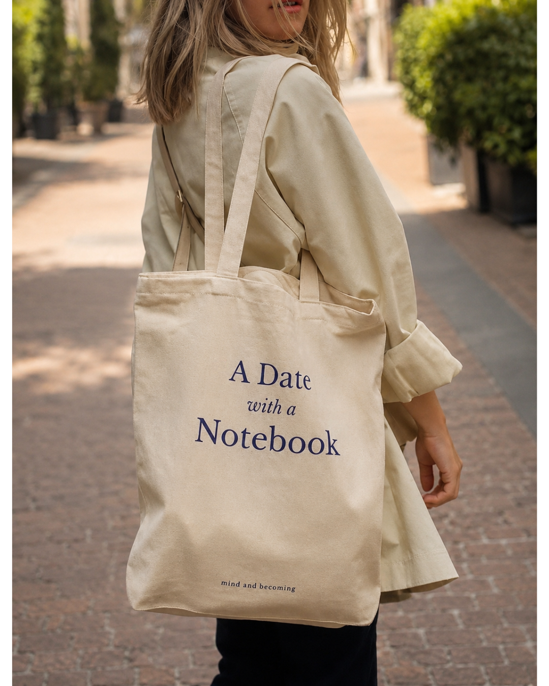 Person holding a beige tote bag with 'A Date with a Notebook' text.