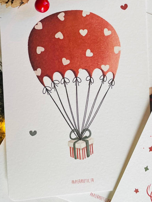 A minimalist art print featuring a brown watercolor hot air balloon with white heart patterns and a striped gift box, shown on a white background with a subtle drop shadow.