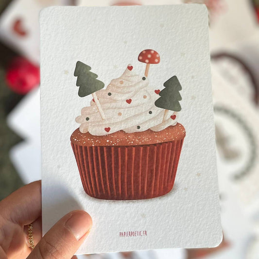 A vertical art print featuring a whimsical illustration of a cupcake with white frosting, decorated with two green Christmas trees, a small red-and-white mushroom topper, and tiny red hearts. The cupcake sits in a brown pleated liner.