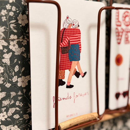 Decorative wall shelf with books against a floral wallpaper background