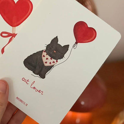 Hand holding playing cards with dog and heart designs on a wooden surface.