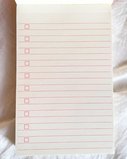 Notebook page with red lines and checkboxes on a textured surface