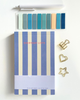 Notebook with blue and beige striped cover titled 'Everyday Lists' on a beige fabric background.