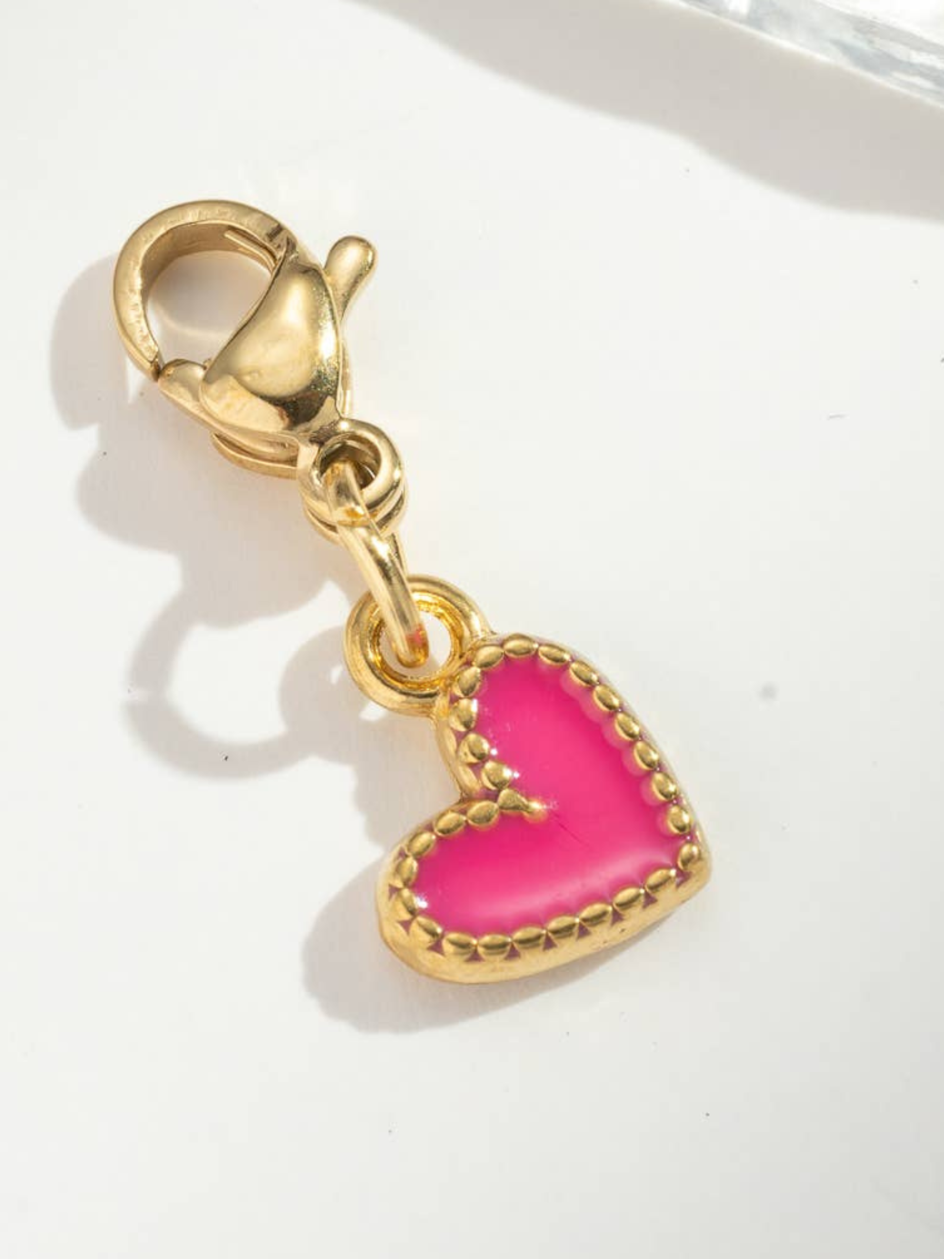 Gold charm with a pink heart on a white background