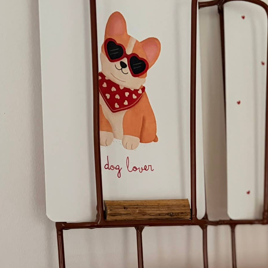 Decorative wall shelf with greeting cards featuring a dog illustration and text.