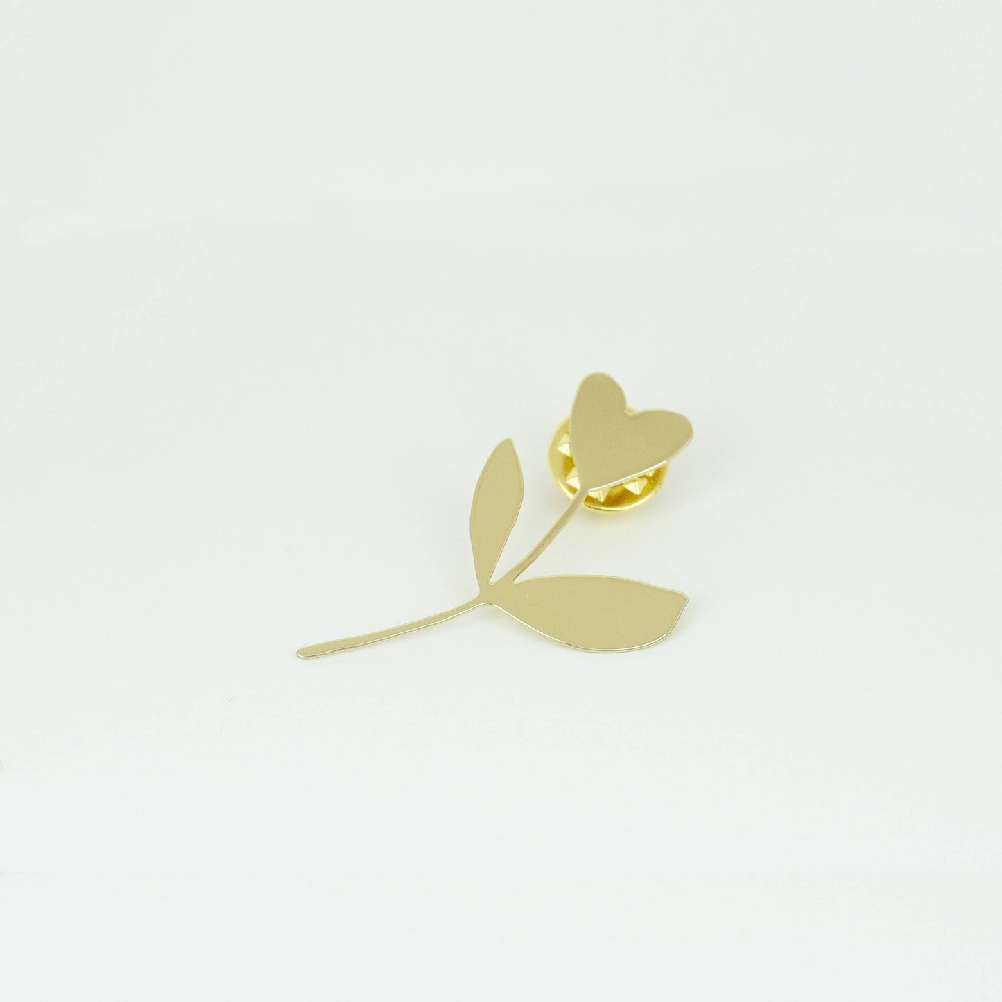 Gold flower-shaped earring on a light gray background