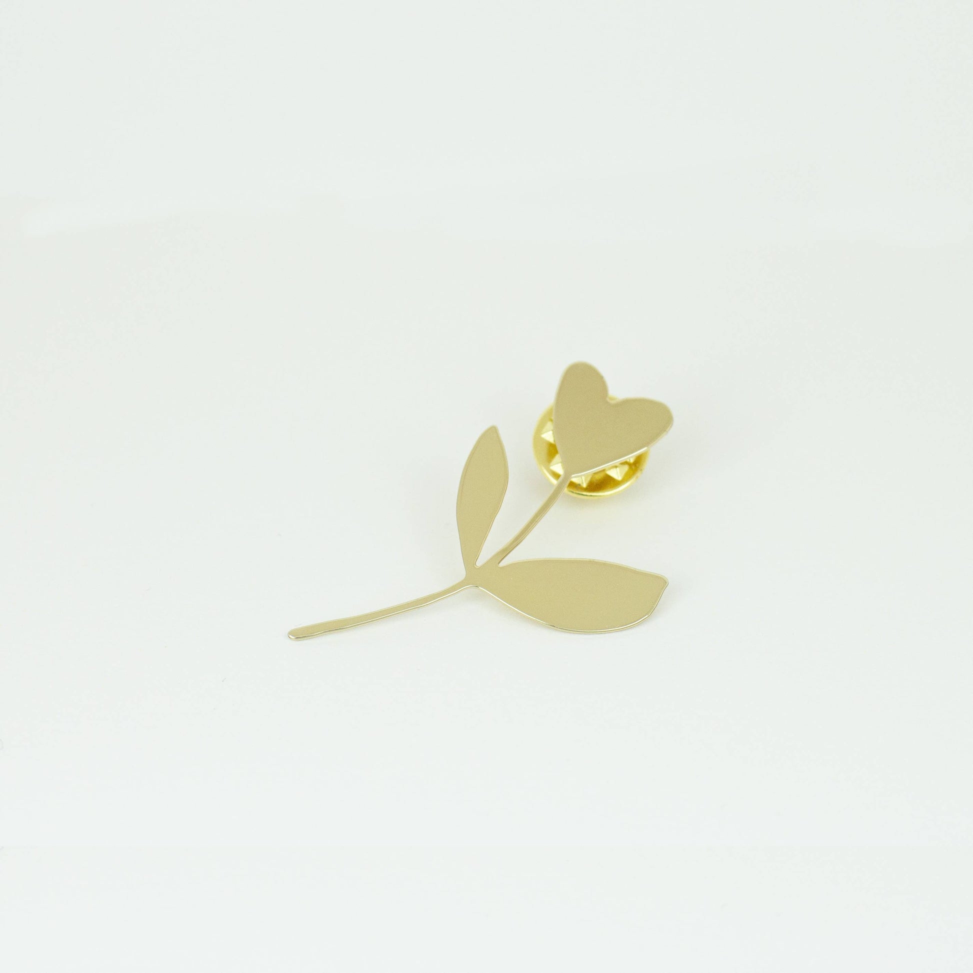 Gold flower-shaped earring on a light gray background
