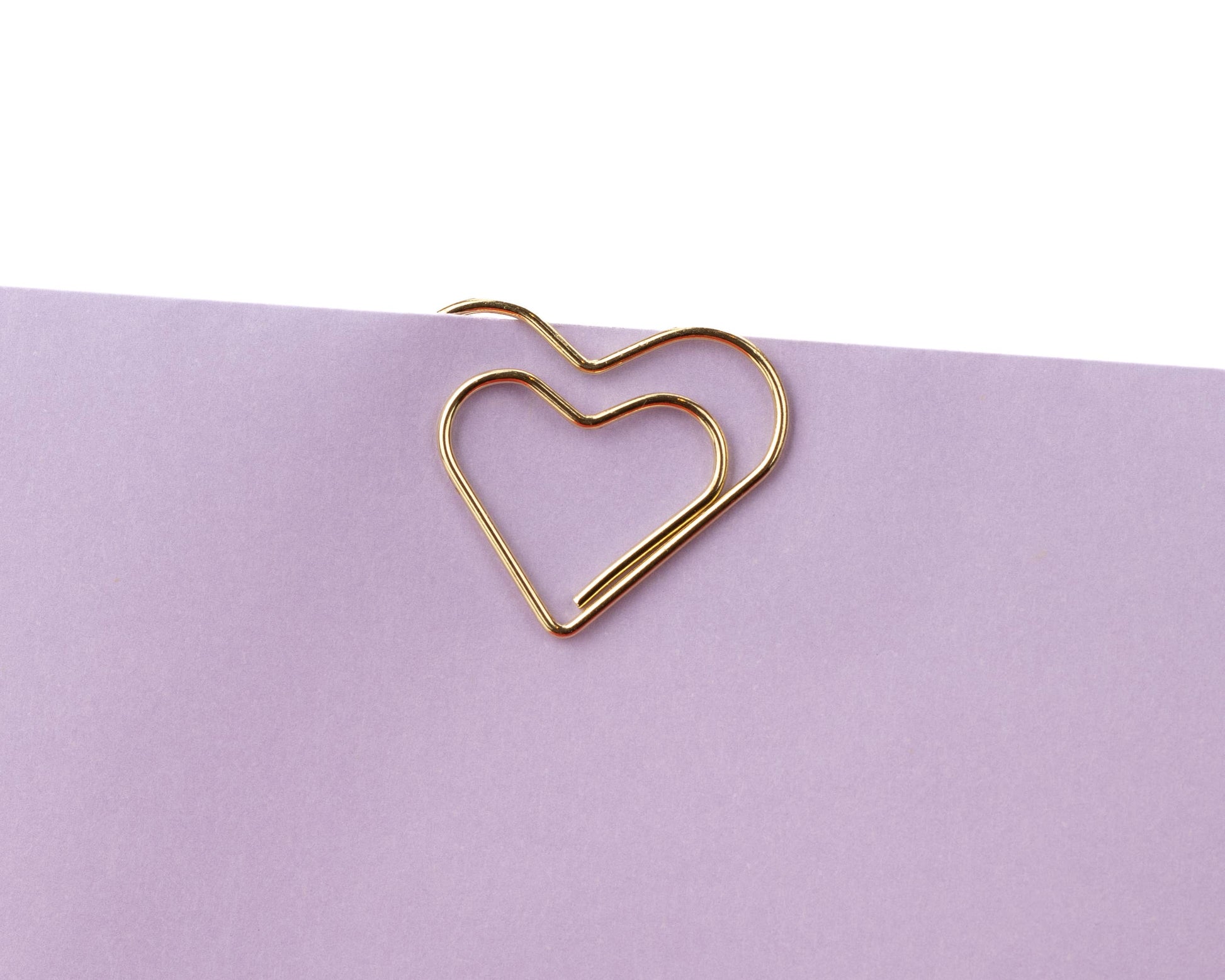 Gold heart-shaped paper clip on a purple background