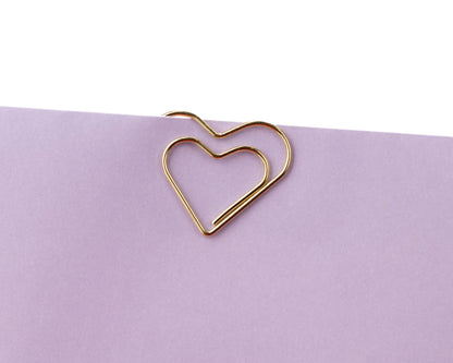 Gold heart-shaped paper clip on a purple background