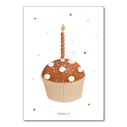 A square art print or card featuring a decorated cupcake with a single lit candle on a white background, with small scattered star-like specks and the text 'PAPIEROSTIQUE.FR' at the bottom.