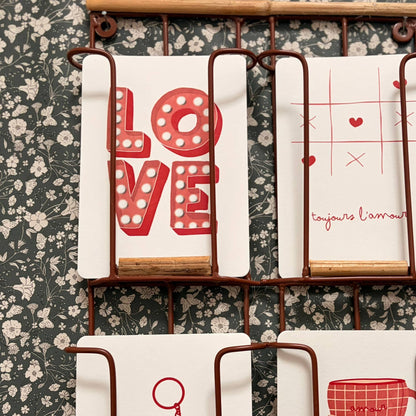Set of tea towels with decorative designs on a floral-patterned wall.