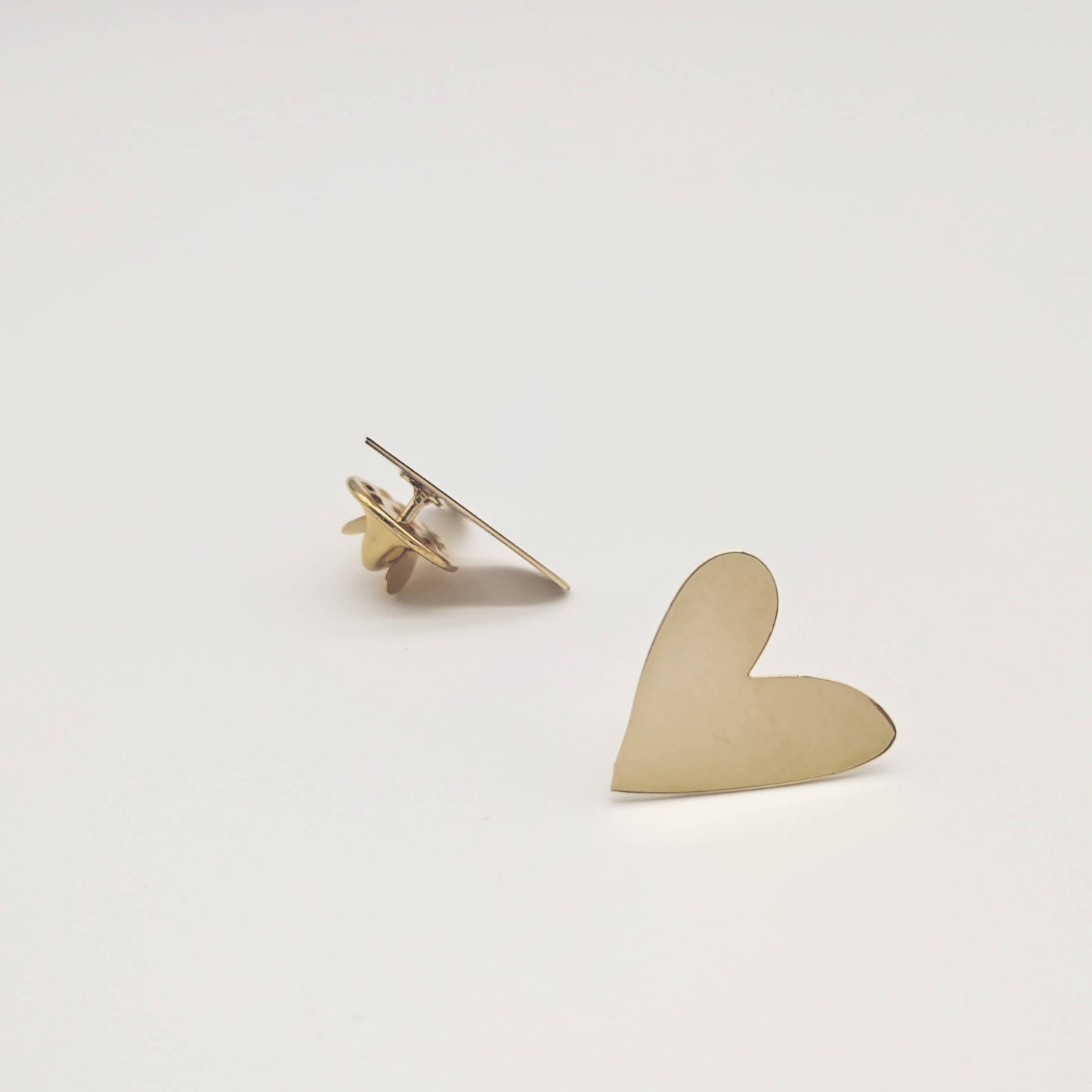 Gold heart-shaped earring on a light gray background