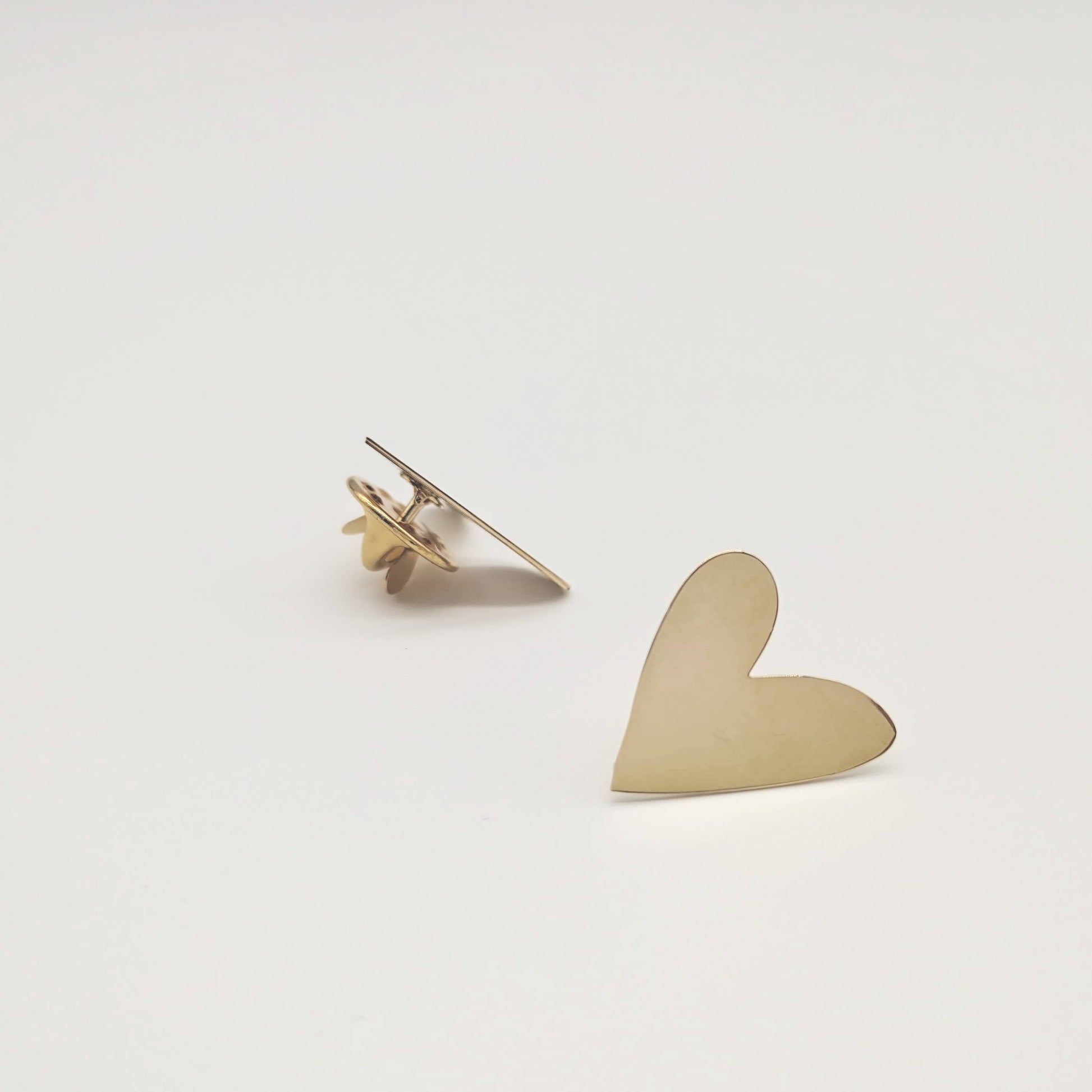 Gold heart-shaped earring on a light gray background