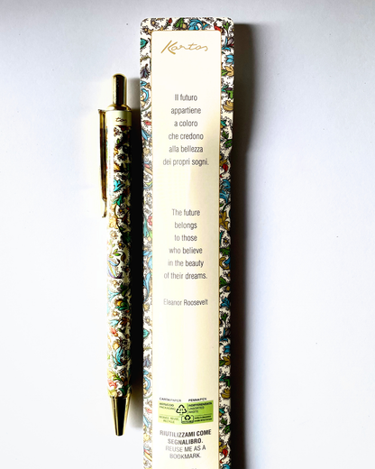 A gold-plated ballpoint pen with ornate multicolor floral enameled detailing, displayed next to its cream-colored packaging box featuring Italian and English text and a quote by Eleanor Roosevelt.