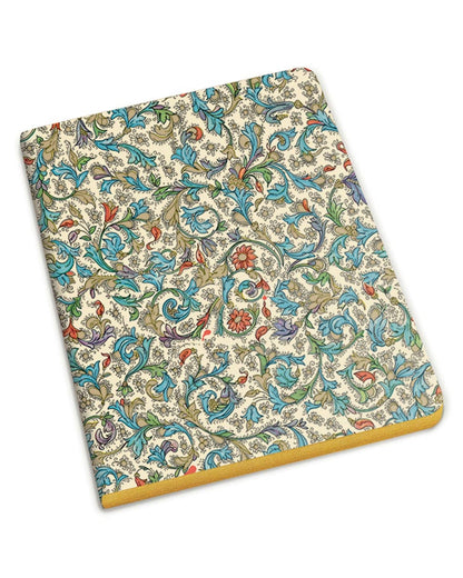 A slim notebook with an intricate multicolor floral and paisley pattern on a cream background, featuring a gold-colored edge, shown on a plain white background.