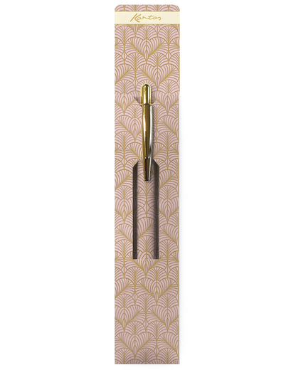 A gold and black metal hair pick with a decorative beige and gold patterned backing card, shown against a plain white background.