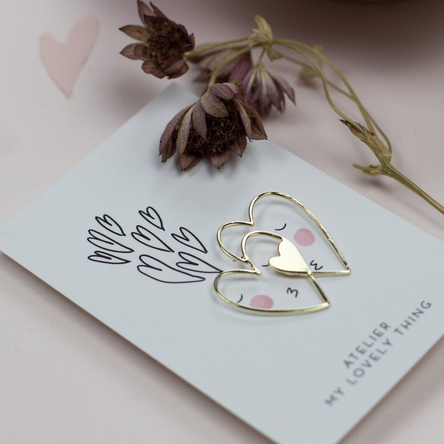 Gold heart-shaped earring on a card with floral elements