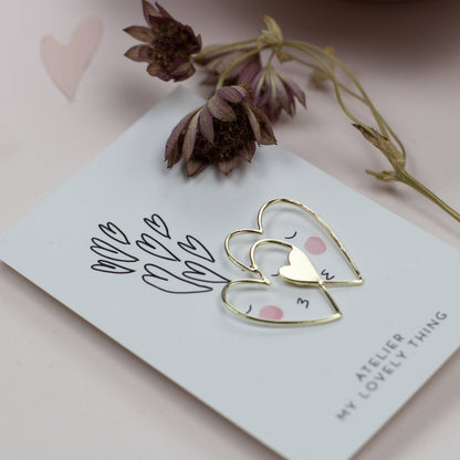 Gold heart-shaped earring on a card with floral elements