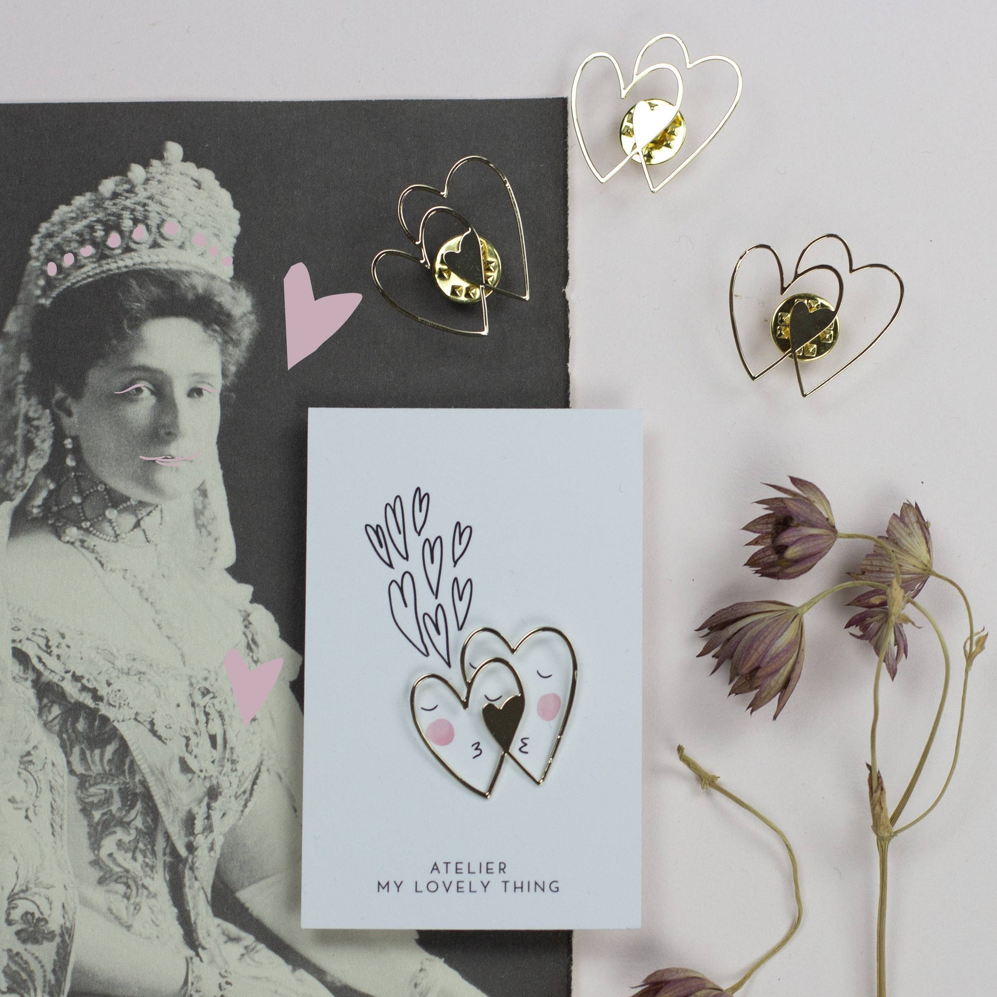 Heart-shaped earrings on a card with a vintage portrait and dried flowers.