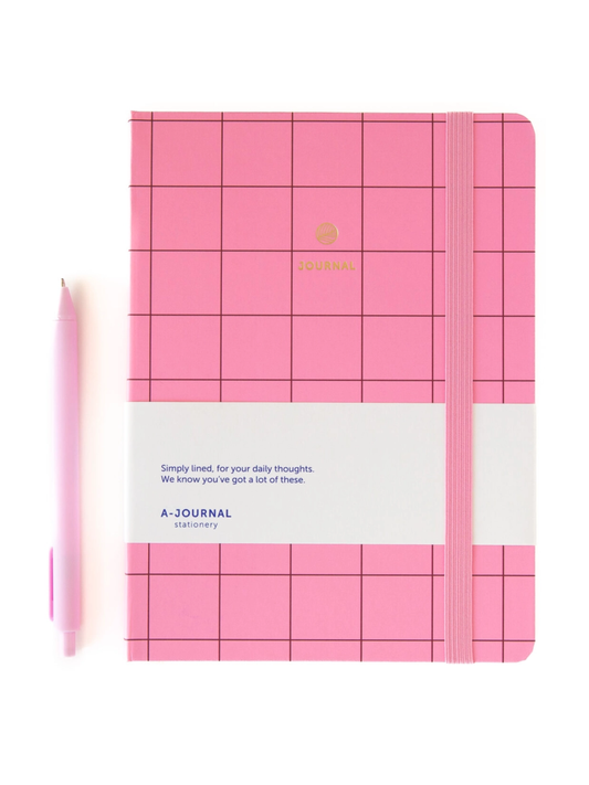 Pink grid-patterned hardcover journal with a white paper band around the middle and an elastic closure, photographed on a plain white background.