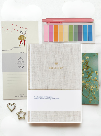 Notebook with colorful sticky notes, pen, and decorative items on a white background