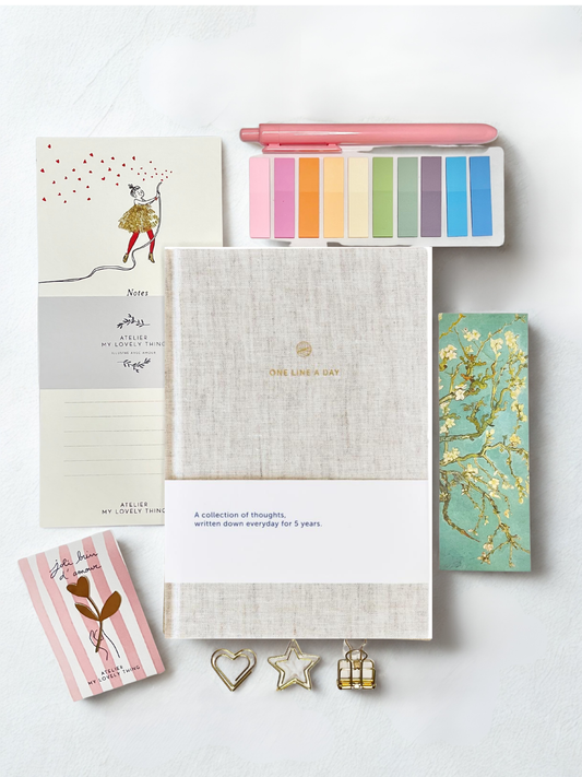 Collection of stationery items including notebooks, stickers, and decorative charms on a white background