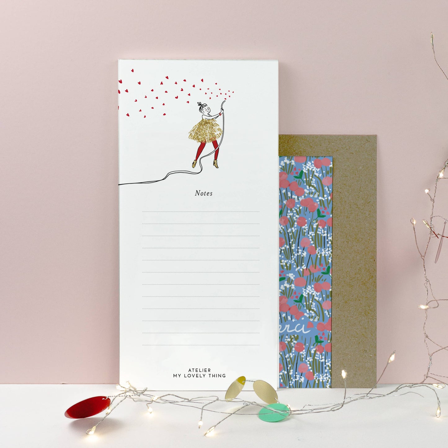 Notepad with artistic design and floral patterned card on a light pink background