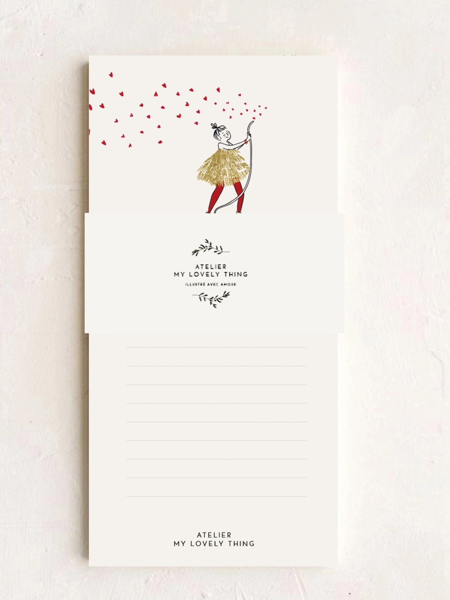 A vertical cream-colored notepad with a whimsical illustration of a girl drawing in the clouds, featuring the brand name 'Atelier My Lovely Thing' printed on the cover, set against a textured light beige background.