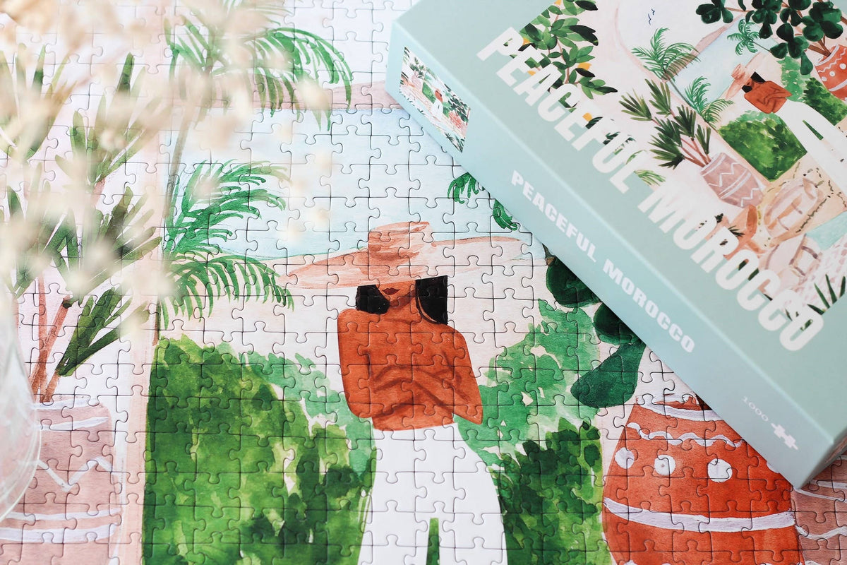 Jigsaw puzzle with a completed section showing two people in a garden, next to a box labeled 'Morocco'.
