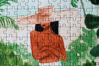 Jigsaw puzzle with a partially completed design of a person in a hat and sunglasses against a green leafy background.