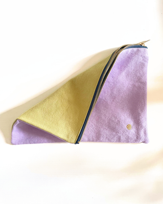 A light purple fabric pouch with a gold zipper and a small gold logo on the bottom right, shown against a plain white background.
