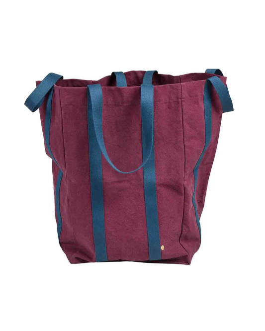A large canvas tote bag in burgundy with dark teal-blue handles and side trim, shown against a plain white background.