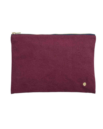 A rectangular zippered pouch in textured magenta suede with a gold zipper and a small gold logo emblem on the bottom right, set against a plain white background.
