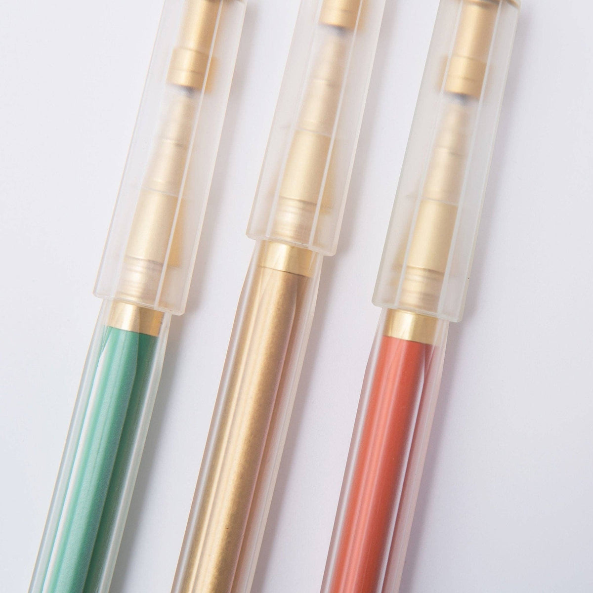 Three pens with gold accents and colored barrels on a white background