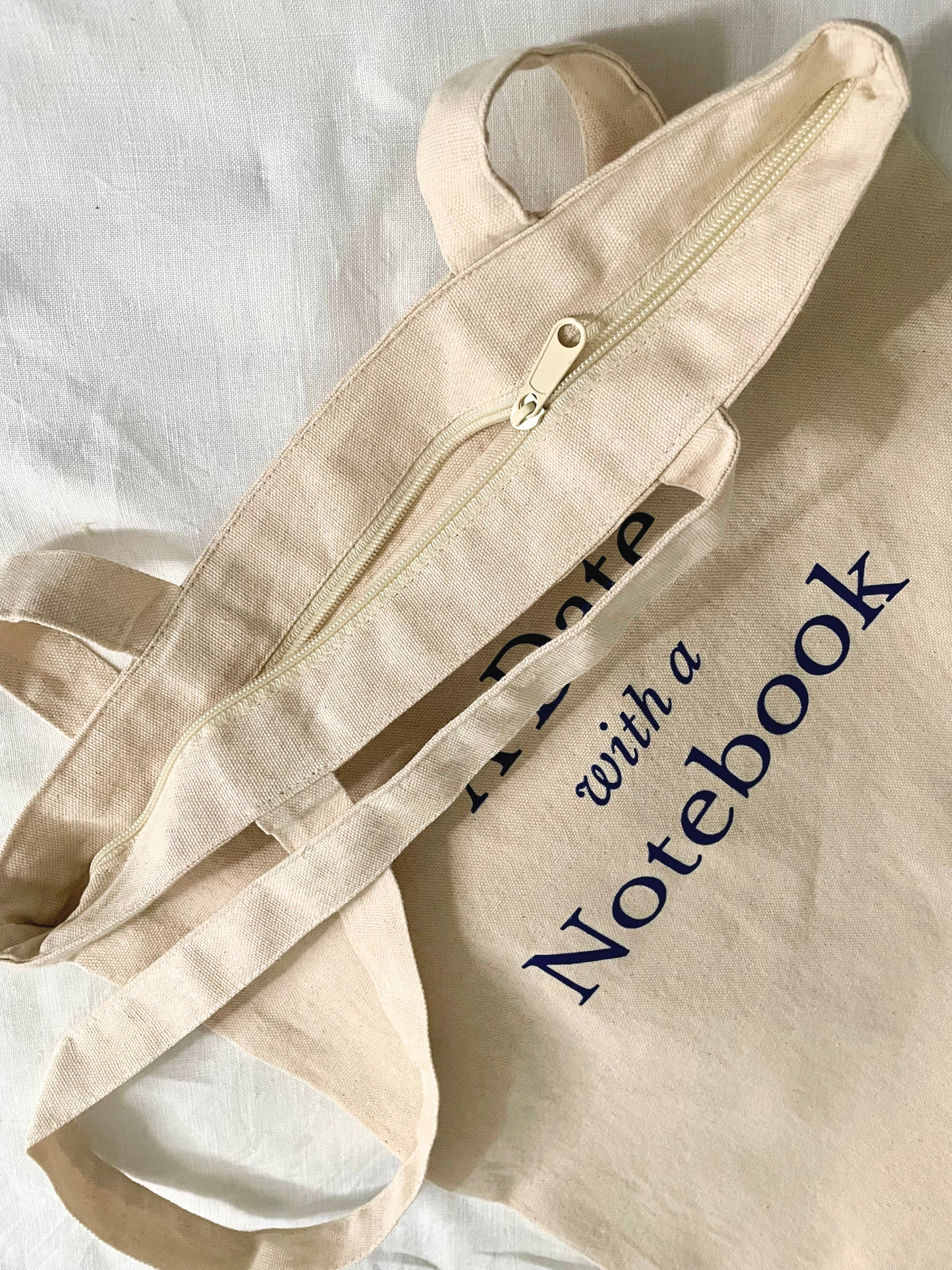 Beige tote bag with a zipper on a white fabric background