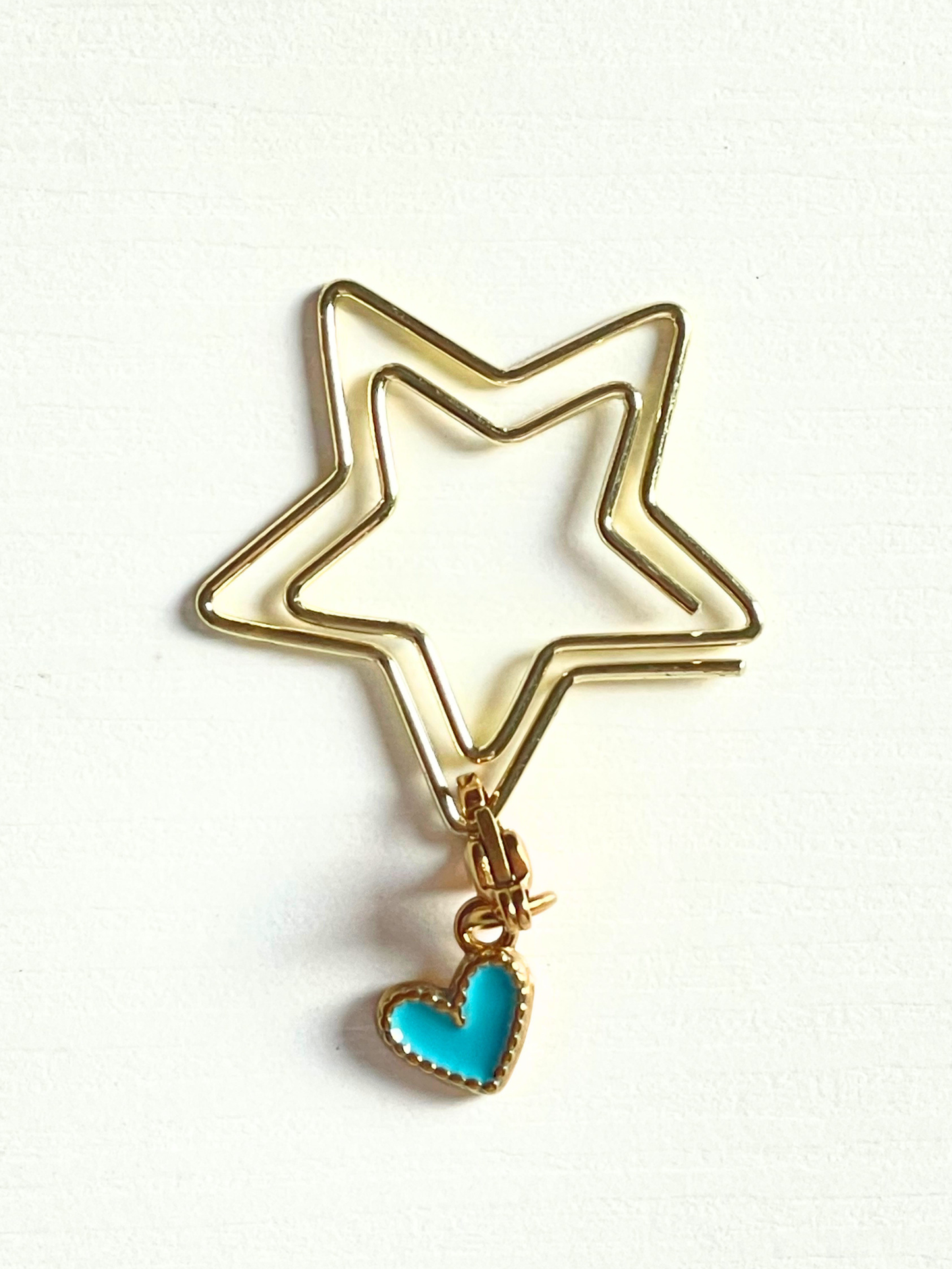 Gold star-shaped keychain with a turquoise heart charm on a white background