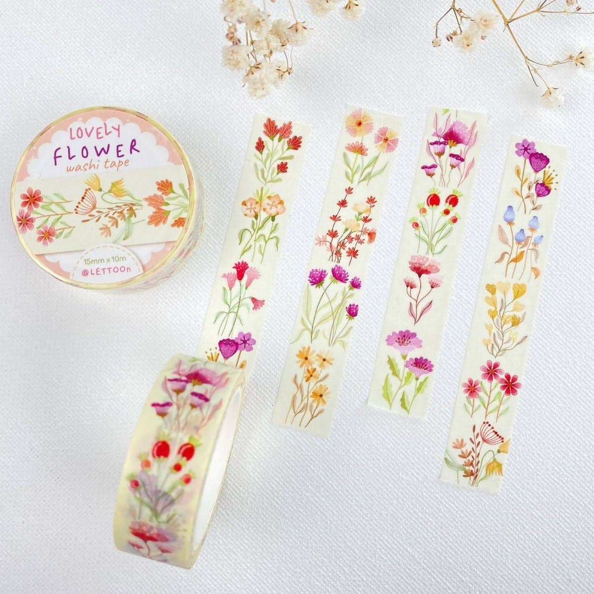 A roll of decorative washi tape labeled 'Lovely Flower washi tape' is shown beside several flat strips of the same tape featuring colorful watercolor-style floral prints on a white textured background.
