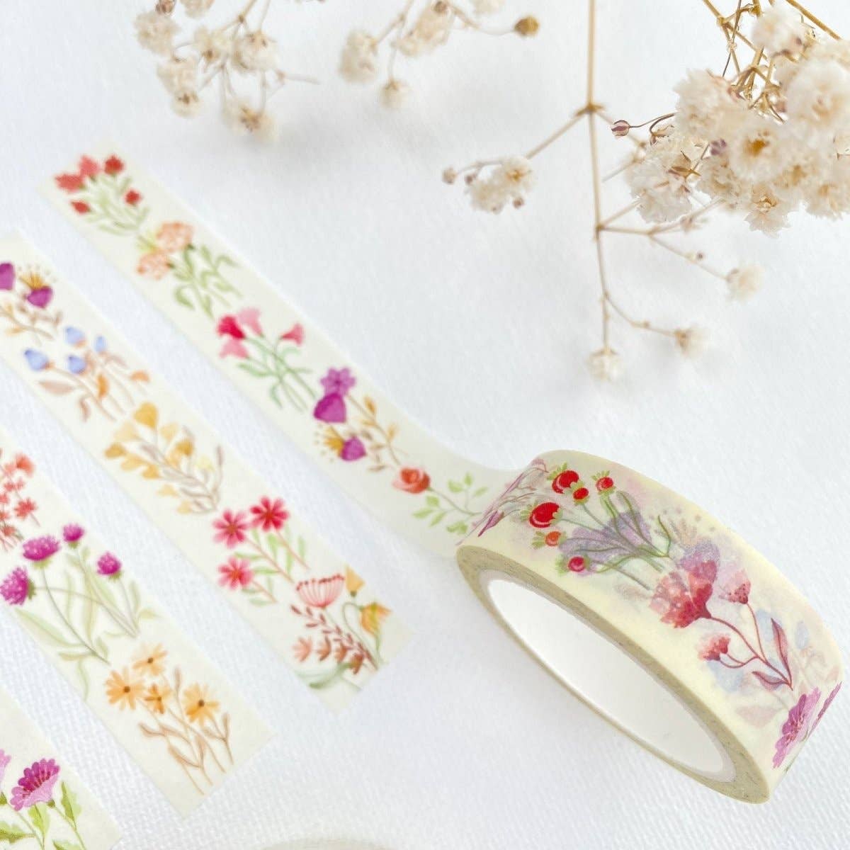 Floral-patterned tape with a roll on a white background with dried flowers.