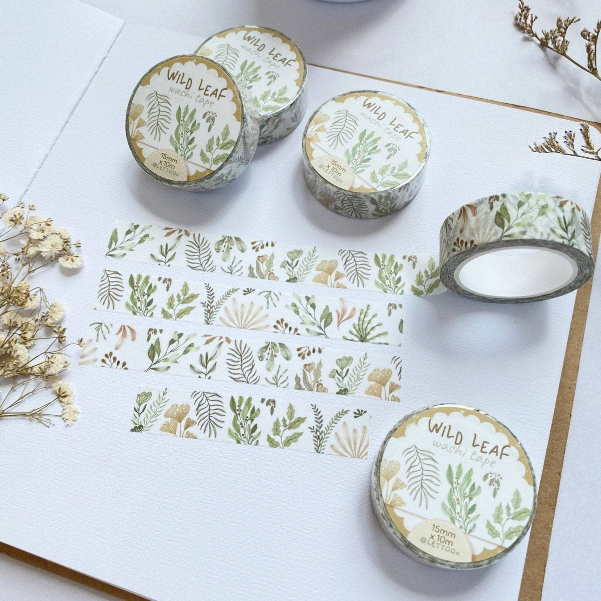 Washi tape with 'Wild Leaf' design on a white surface with flowers.