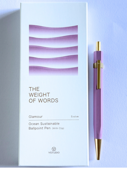 A lavender purple ballpoint pen with gold accents stands next to its white packaging box, which features the text 'THE WEIGHT OF WORDS' and 'Glamour Evolve Ocean Sustainable Ballpoint Pen (With Clip)' by YSTUDIO.