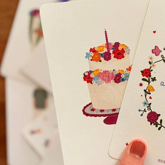 Colorful birthday cake with flowers and a candle on a white background