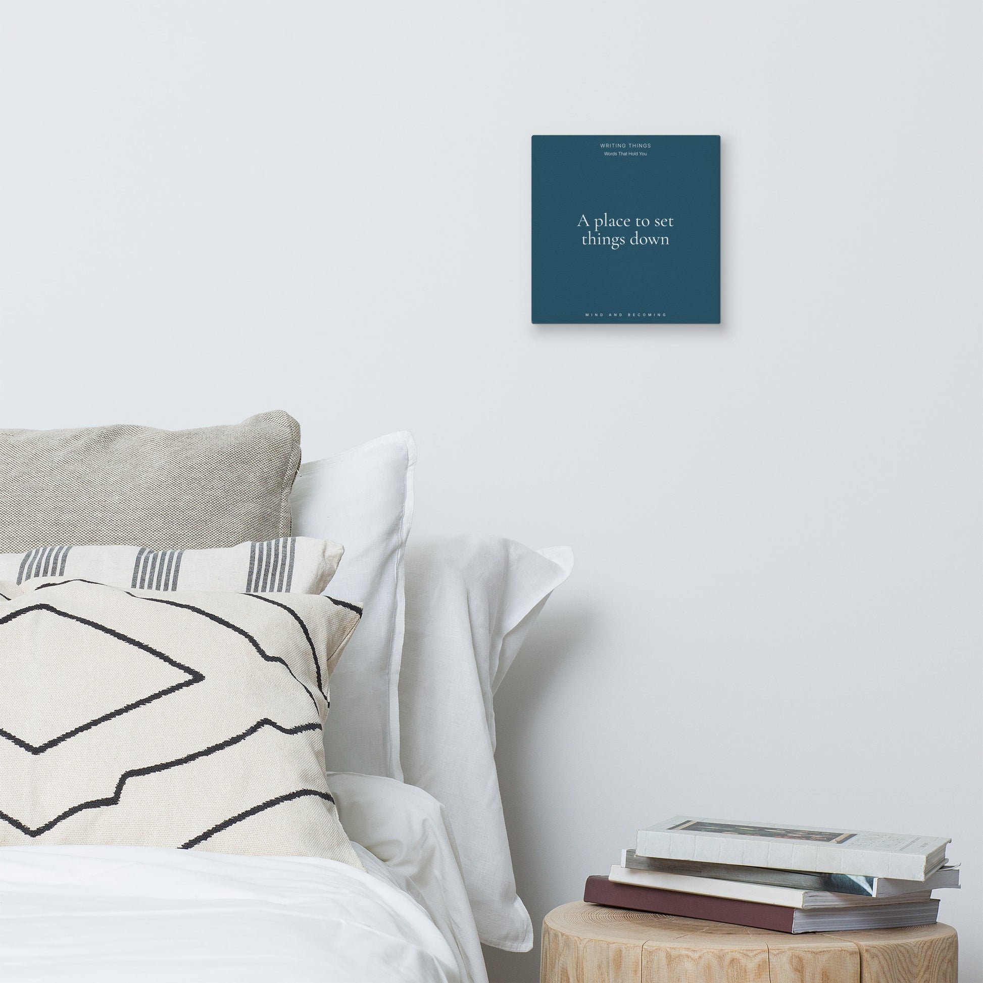 Bedroom with a bed, pillows, and a small table with books, featuring a motivational poster on the wall.