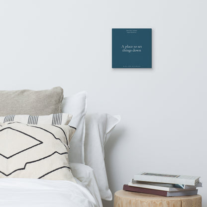 Bedroom with a bed, pillows, and a small table with books, featuring a motivational poster on the wall.